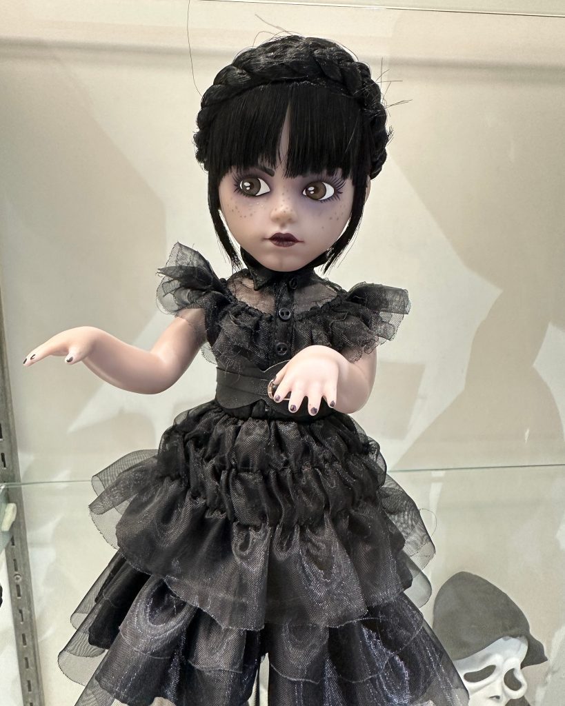 A Wednesday Addams doll with long black braided hair wearing a black dress and black shoes. The doll is modeled after actress Jenna Ortega's portrayal of Wednesday in the 2022 Netflix series.

SDCC 2023 toy.